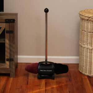 A shoe polishing machine with a brush and stand on a wooden floor.